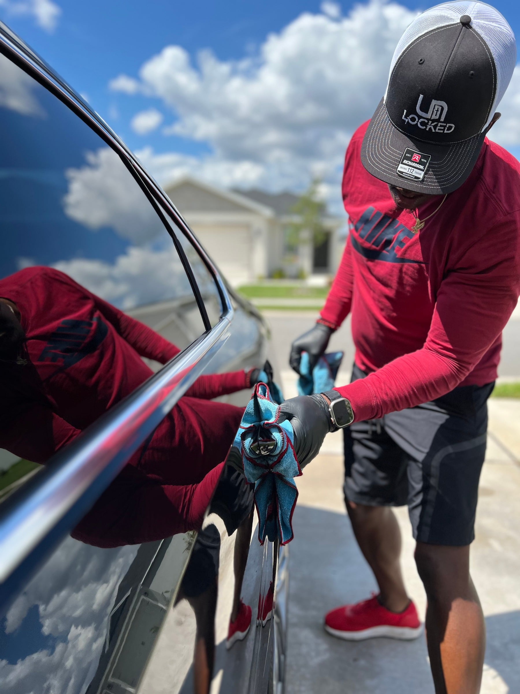 Owner in a red shirt carefully detailing a car door by hand