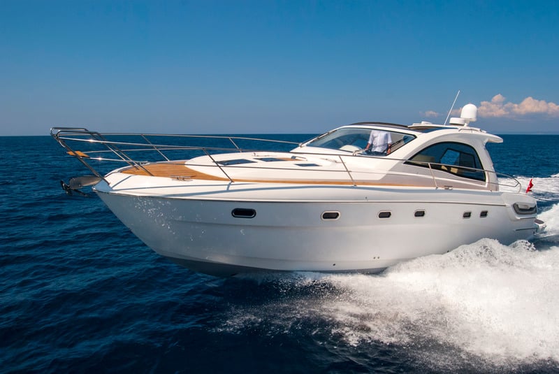 A white boat resting on bright blue water, freshly detailed and gleaming